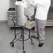 A man in a white coat and gray pants using a Hobart 6115-PSTAND in a commercial kitchen.