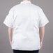 A man wearing a white Chef Revival short sleeve cook shirt with the sleeves rolled up.