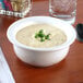 A white Tuxton china pot pie bowl filled with soup on a table.