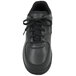 A close-up of a Genuine Grip black leather athletic shoe with laces.