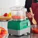 A person using an AvaMix commercial food processor to chop tomatoes.