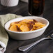 An oval Hall China baker dish filled with potato chips on a table.