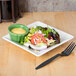 A plate of salad with a fork on a Homer Laughlin Ivory square plate.