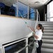 A woman using an Unger window cleaning kit to clean white stairs.