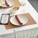 A table setting with RITZ tan, orange, and rust basketweave placemats and wine glasses.