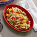 A Tuxton oval china platter with pasta salad, tomatoes, and cheese on it.