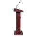 A wooden lectern with a mahogany finish and an attached microphone.