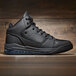 A black Shoes For Crews Tigon athletic shoe on a wood surface.