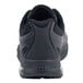 The back view of a Shoes For Crews black athletic shoe with a non-slip bottom.
