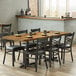 A rectangular wood butcher block table with vintage finish on a table with plates and chairs.