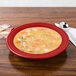 A Fiesta china rim soup bowl filled with soup on a table with a spoon.