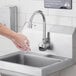 A person washing their hands under a wall mounted Equip by T&S sensor faucet.