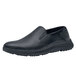 A black Shoes For Crews men's slip on shoe with a white background.