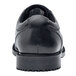 A close up of a black leather Shoes For Crews men's dress shoe with a rubber sole.