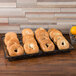 A rectangular wrought iron pastry basket with a scroll design holding a tray of bagels on a bakery counter.