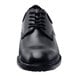 A close up of a black Shoes For Crews Cambridge men's dress shoe with laces.