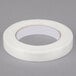 A roll of Shurtape white fiberglass reinforced strapping tape on a gray surface.