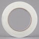 A roll of Shurtape white fiberglass strapping tape with a clear circle on the roll.