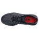 A black Shoes For Crews athletic shoe with a red sole.