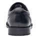 A close up of a black leather men's Shoe For Crews Cambridge dress shoe with a rubber sole.