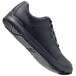 A black Shoes For Crews athletic shoe with orange accents.