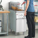A stainless steel floor fryer with two baskets being used in a commercial kitchen.