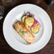 An Arcoroc Vintage dinner plate with salmon and vegetables on a table.