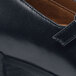 A close up of a black leather shoe with a side buckle.