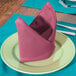 A folded mauve cloth napkin on a plate.