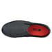 A black Shoes For Crews slip-on shoe with red soles.