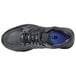 A black Shoes For Crews athletic shoe with a blue sole.