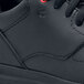 A close up of a black Shoes For Crews Liberty athletic shoe on a table.