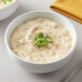 A bowl of soup with green onions and a spoon on a white background.