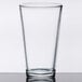 A Libbey clear mixing glass on a table.