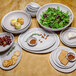 A table with GET Pottery Market melamine platters, bowls, and crackers with food in them.