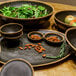 GET brown melamine bowls with clay trim filled with green salad and apples on a table.