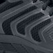 A close up of a black and grey Shoes For Crews Stride men's athletic shoe with a reflective stripe.