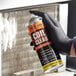 A person wearing gloves holding a can of Noble Chemical Tech Line Expanding Foam Coil Cleaner.