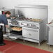 A woman putting food into a large oven in a professional kitchen.