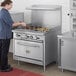 A woman cooking burgers on a Cooking Performance Group commercial gas range with a griddle.