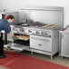 A man using a Cooking Performance Group commercial range with two large ovens to cook food.