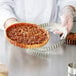 A hand using a Gobel round fluted tart pan to bake a pie.