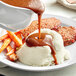 A plate of mashed potatoes and carrots with LeGout beef gravy poured over them.