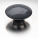 A close-up of a black knob on a silver surface.