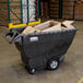 A large black Rubbermaid trash cart full of cardboard boxes.