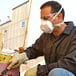 A man wearing a 3M P100 particulate respirator and gloves is working on a piece of equipment.