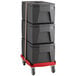 A stack of black plastic boxes on a red cart with a brown strap.