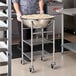 A man in a chef's uniform using a Choice stainless steel mixing bowl on a stand.