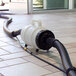 A white and black plastic container with a hose connected to a vacuum cleaner.