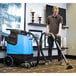 A man in a brown shirt using a Mytee carpet extractor to clean a carpet.